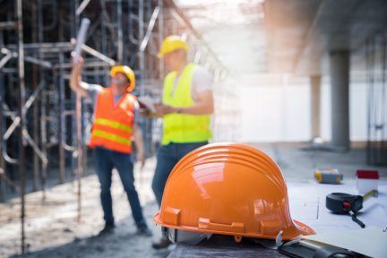 The yellow safety helmet in construction site and construction site worker background safety first concept.